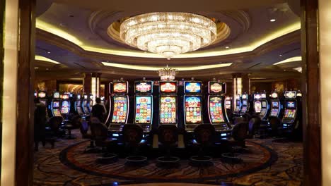 illuminated casino interior showcasing a row of slot machines under a glorious chandelier, capturing the euphoria and excitement of gaming entertainment
