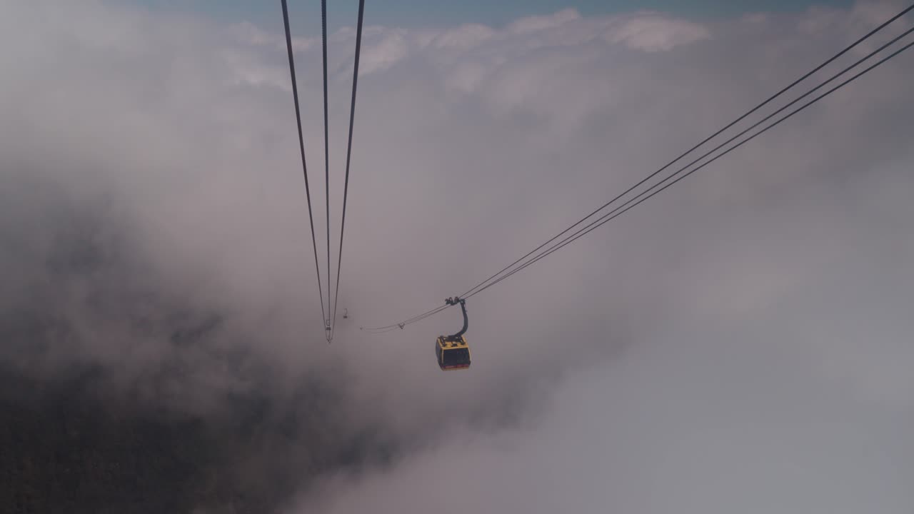 Funivia che si muove tra le nuvole in alta montagna