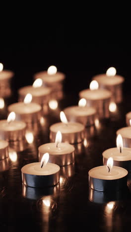 vertical video of lit tea candles and copy space on black background