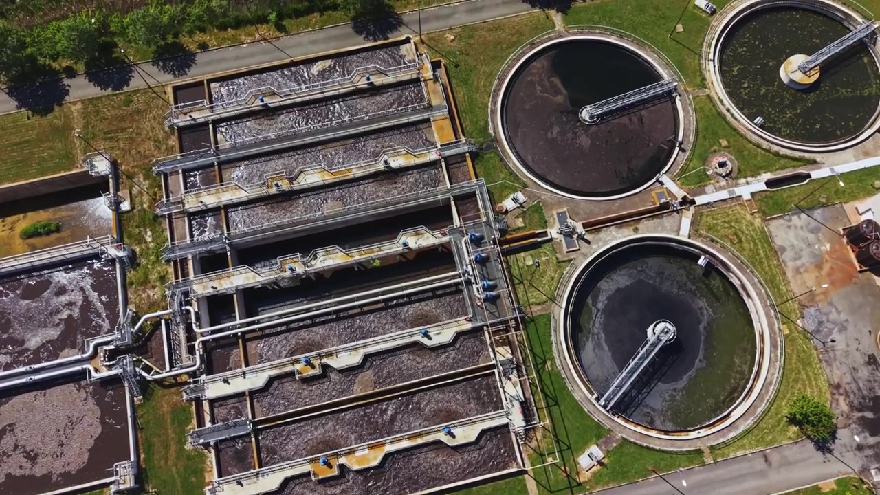 Industrial plant overview. Circular clarifiers and aeration lanes in sewage plant. Highangle drone shot of industrial sewage treatment facilities and surrounding environment