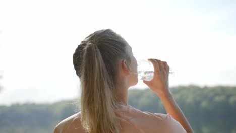 Frau-Trinkt-Wasser-Aus-Der-Flasche-Vor-Dem-See