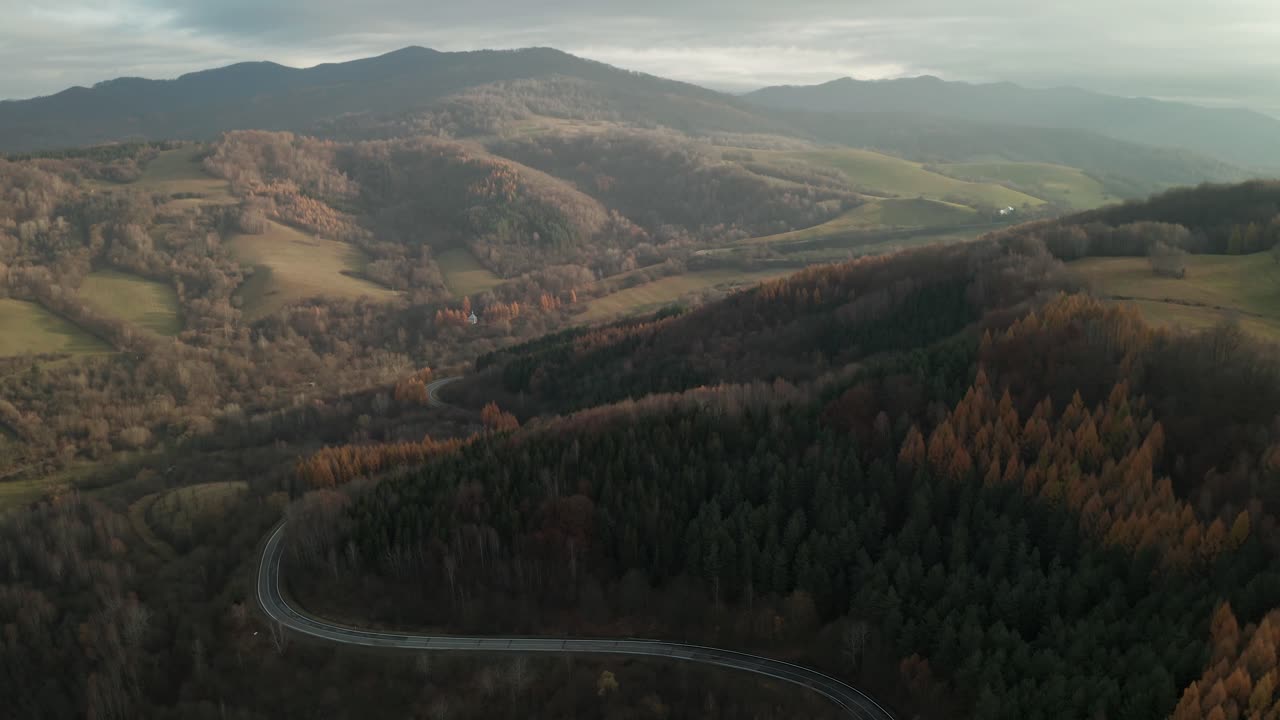 An aerial ascending drone shot of winding road running through the beautiful National Park Poloniny, Slovakia in late autumn