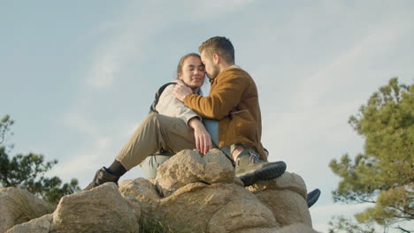 pareja romántica sentada en la cima de la montaña y besándose