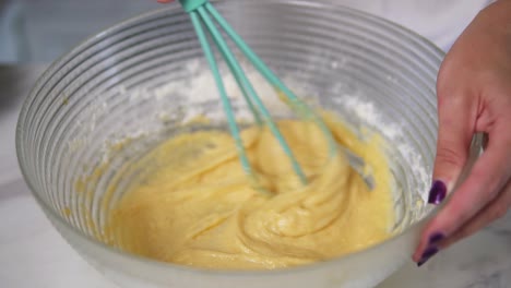 Close-Up-view-of-female-hands-preparing-dough-mixing-ingredients-using-whisk-in-the-kitchen.-Homemade-food.-Slow-Motion-shot