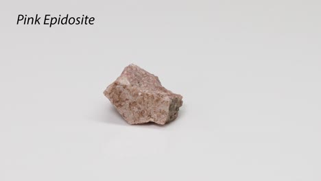 pink epidosite rock rotating on white background