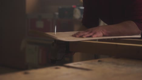 a carpenter saws a skateboard out of a wooden board using a jigsaw