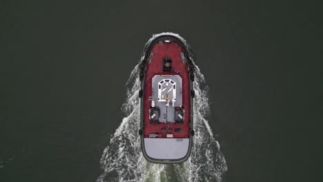 an aerial view high above a lone tugboat on a cloudy morning in the hudson river, near brooklyn, ny