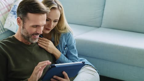 pareja madura usando una tableta en la sala de estar