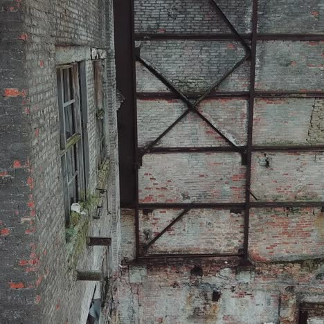 flight over the destroyed factory. facade of old industrial building for demolition, broken glass and destroyed frames.