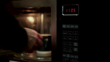 man taking a mug out of the microwave