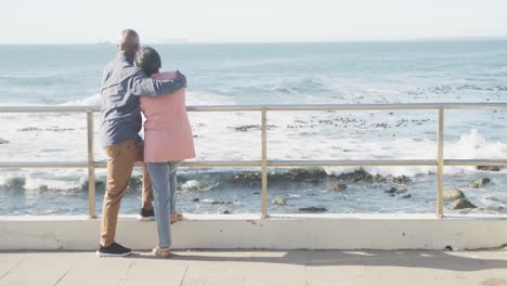 happy senior african american couple embracing on promenade by the sea, copy space, slow motion