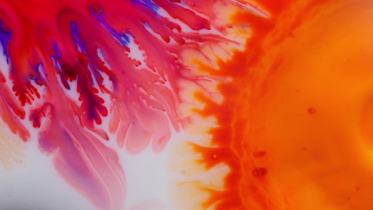 Abstract macro shot of alcoholic ink forming vibrant red, pink, and orange patterns