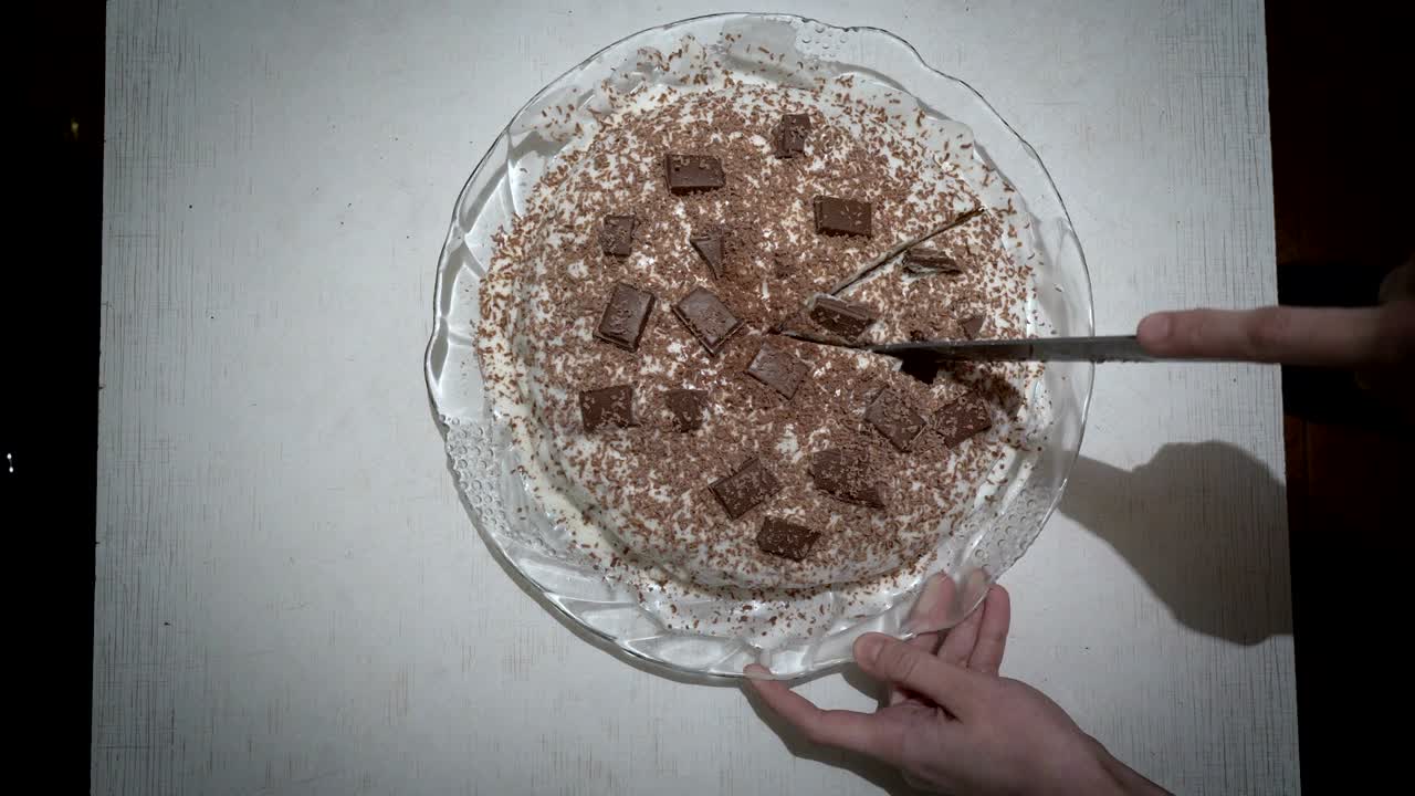 한 여성이 초콜릿 조각으로 장식된 둥근 케이크를 잘라 으로. 얼굴이없는. 가정 축제. 가까운. 위에서 볼 수 있는.