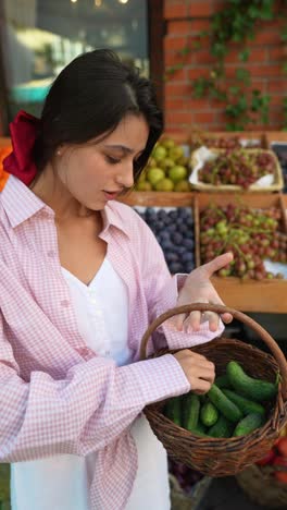 mujer comprando pepinos en un mercado de agricultores