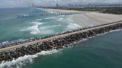 Ocean-Waves-On-Sandy-Beach-Between-Sand-Bypass-Pumping-Jetty-And-The-Spit-Seawall-In-QLD,-Australia