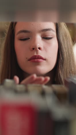woman looks at books on shelf in library. concentrated student chooses literature materials for essay writing in bookcase closeup. constant reader