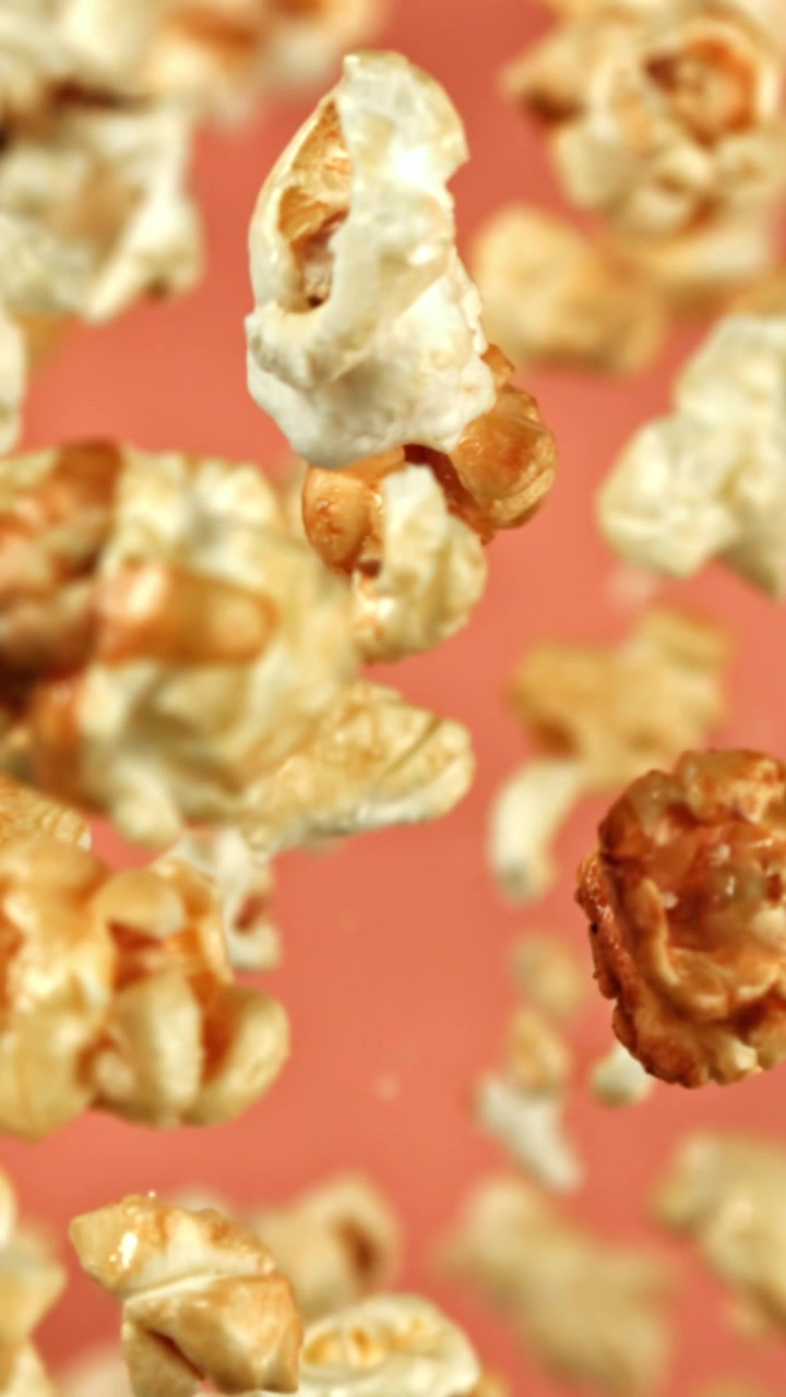 Popcorn dolci al caramello che cadono al rallentatore su sfondo rosa