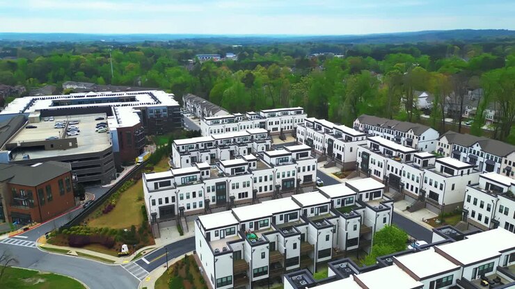 Weiße moderne Reihenhäuser in einem amerikanischen Viertel mit Flachdächern. Grüne Bäume im Hintergrund. Frühlingstag in einem Vorort von Atlanta, Georgia. Weitwinkel-Drohnenaufnahme.