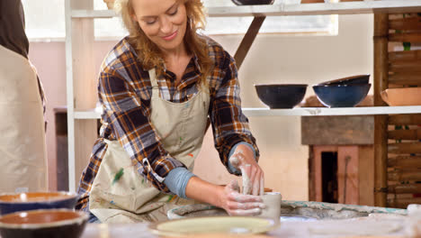 smiling female potter making pot in pottery workshop