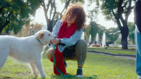 two female friends playing with dogs on green lawn in the park