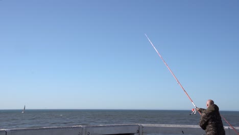 Man-Throws-A-Fishing-Rod-Into-The-Sea---Fishing-In-Nieuwpoort,-Belgium---wide,-static-shot