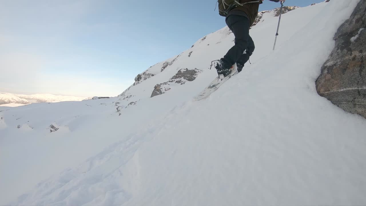 todavía tiro hombre equipado con raquetas de nieve caminando sobre la nieve cuesta arriba - noruega