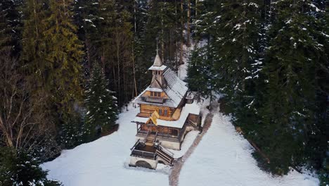 Stunning-Aerial-Shot-of-Jaszczurówka-Chapel-covered-in-Snow-Winter-Drone