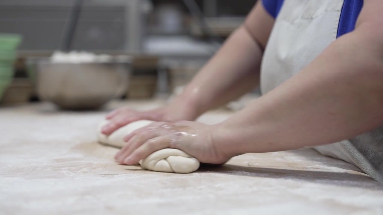 A woman rolling dough in a private bakery, captured in 4K resolution at 60fps, slow motion.
