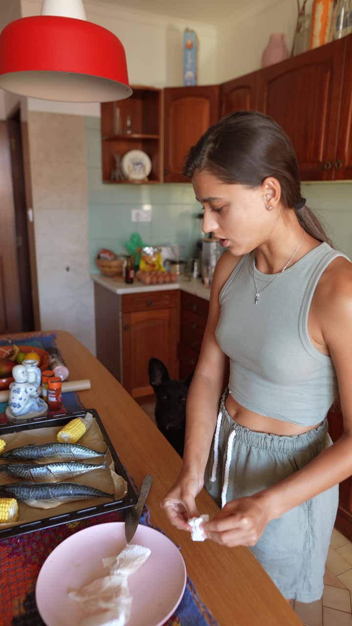 Mulher preparando peixe e milho na cozinha