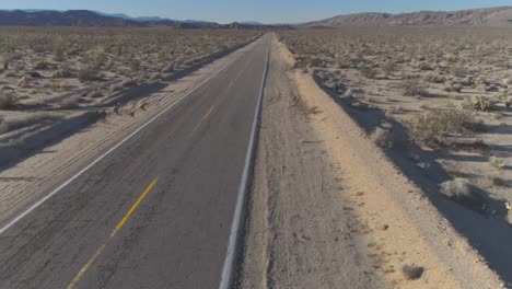 dji phantom 4 pro in the desert of southern california on an open road in between mountains, with a girl walking alongside the road