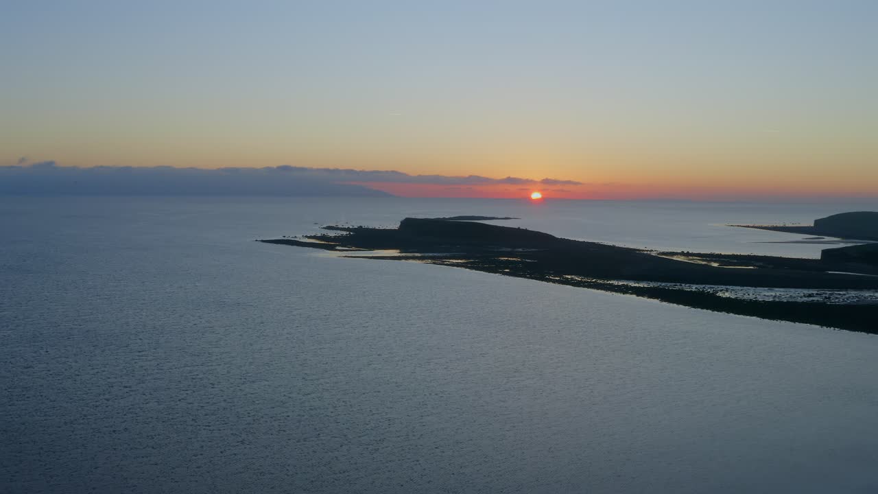 Aerial pullback showcasing a stunning sunset horizon on Galway bay.