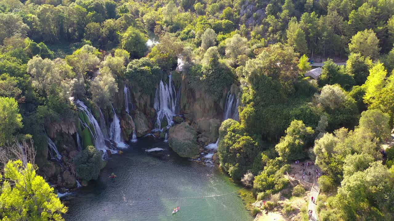 Kravica Waterfall area on the Trebizat river with kayaks and tourists below, Aerial flyover shot