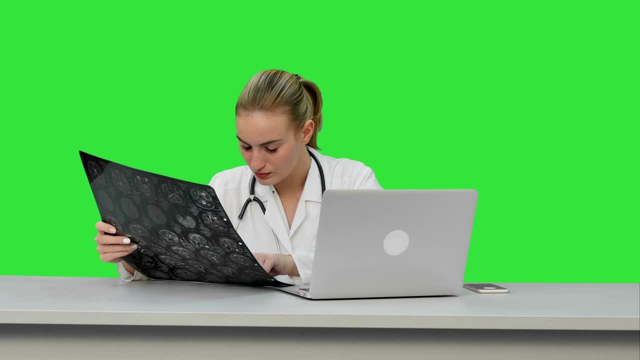 una joven doctora preocupada por el difícil caso de un paciente que vio en una radiografía en una pantalla verde, clave de croma