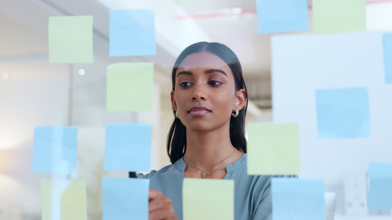 Woman Brainstorming with Sticky Notes on a Glass Wall