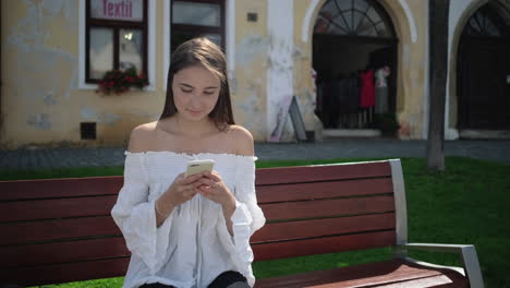 mujer usando un teléfono inteligente en un banco del parque