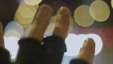 primer plano de la mano en guantes con bokeh de semáforos borrosos en la noche