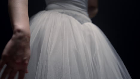 woman arm touching tutu skirt indoors. unknown ballerina hand playing with dress