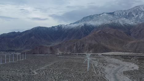 Drones eye view of windmills with snow capped mountain&#039;s in the background