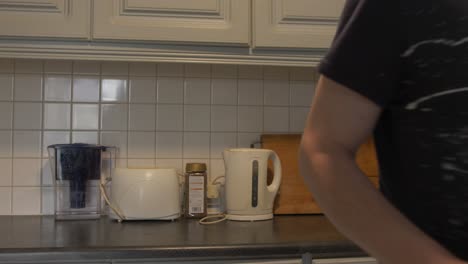 Man-in-kitchen-grabs-prepared-lunchbox-with-waterbottle