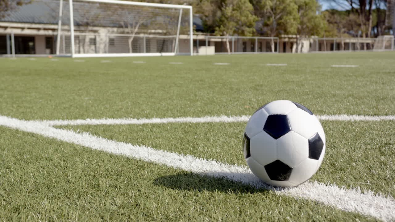 Fodbold på bane nær målstolpe, klar til kamp eller træning, med plads til tekst.