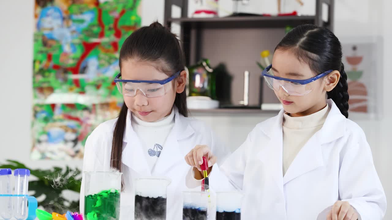 Siswi Asia mengenakan kacamata pelindung menggunakan pipet untuk mencampur cairan di gelas kimia selama percobaan sains.