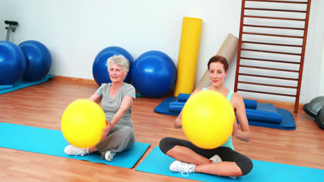 entrenador y cliente anciano levantando bolas de ejercicio