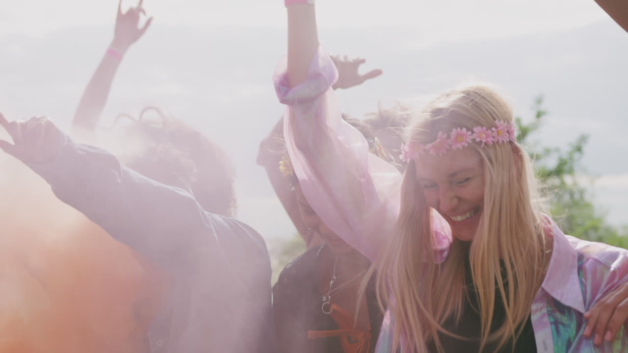 Gruppe unge venner danser bag en barriere ved en udendørs musikfestival