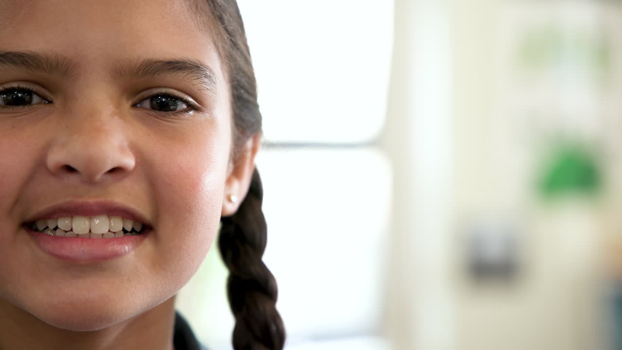 Smiling girl with braided hair enjoying school day in bright classroom, copy space