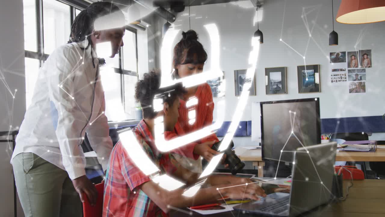 Team typing and gesturing at desk, moving network appearing pulsing shield over laptop for security