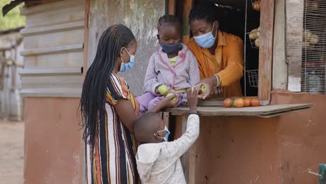 poverty.inequality.black african mother and two young children buy fruit from an informal shop in a slum surrounding.