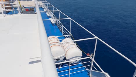 tilt up shot of empty deck of ferry boat cruising the sea, mountain range in horizon, travel concept