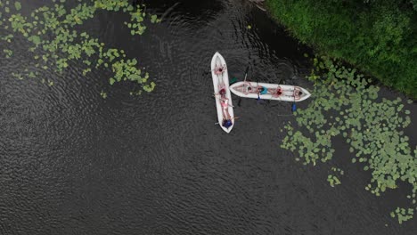 aerial birds-eye view of two canoes filled with people in a river in the wilderness