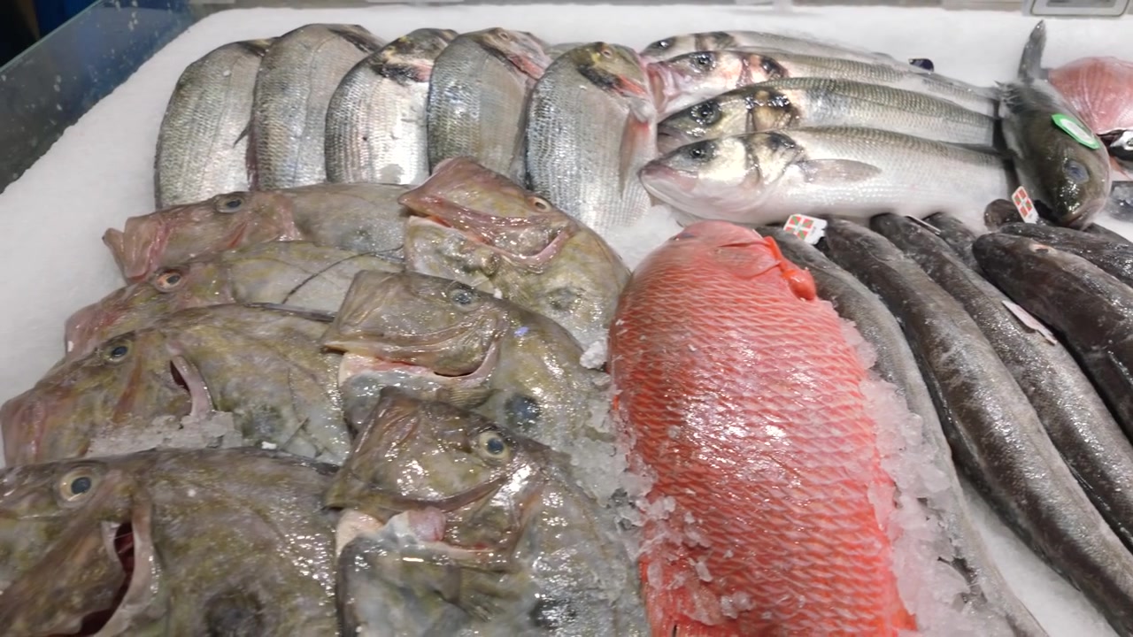 Close-up of assorted fresh fish including sardines and red fish on crushed ice at a seafood market, Cote d'Azur, France