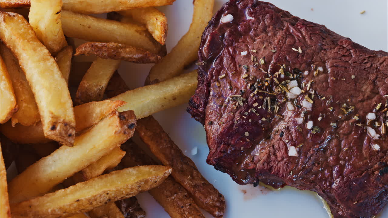 Close up of stake with fries and salad on a white plate at a restaurant